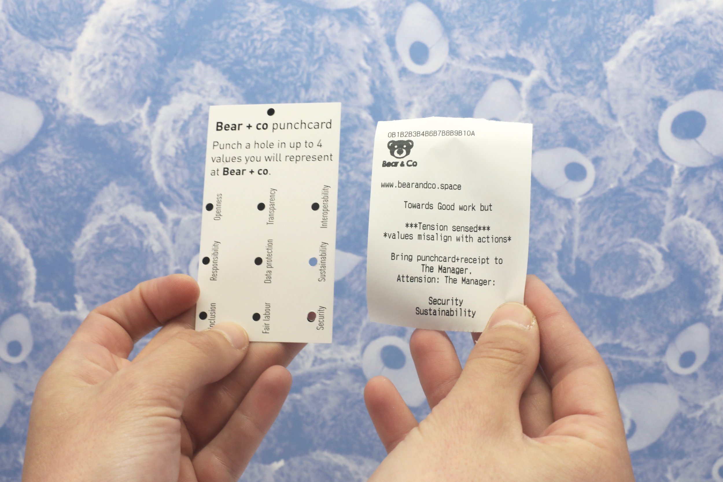 Participant hands holding both the punched value card and the printed receipt side by side, illustrating the values-in-action workflow.