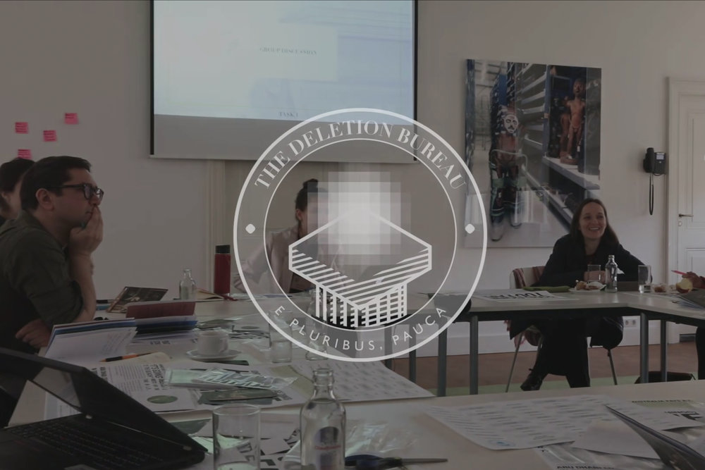 Close-up of a bright orange field case containing a custom āPunchcardā device prototype, with a participantās hand reaching to insert a punchcardādemonstrating the tangible prototyping exercise for interacting with erased heritage objects.