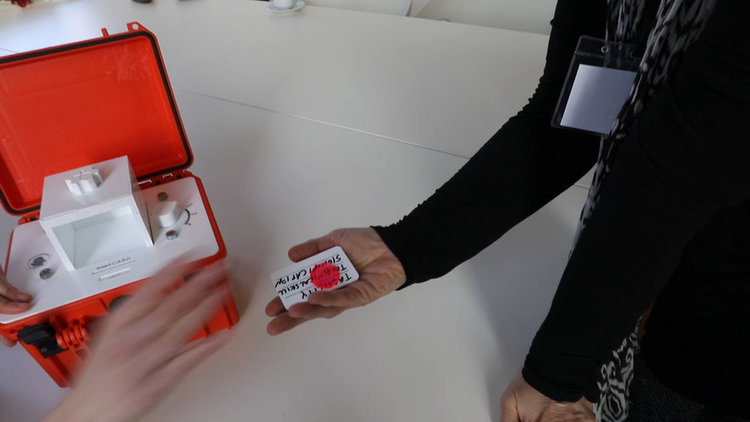 Participant holding a custom punchcard receipt printed with algorithmic output (āE pluribus paucaā), highlighting how deletion algorithms generate tangible artifacts for expert review and reflection.